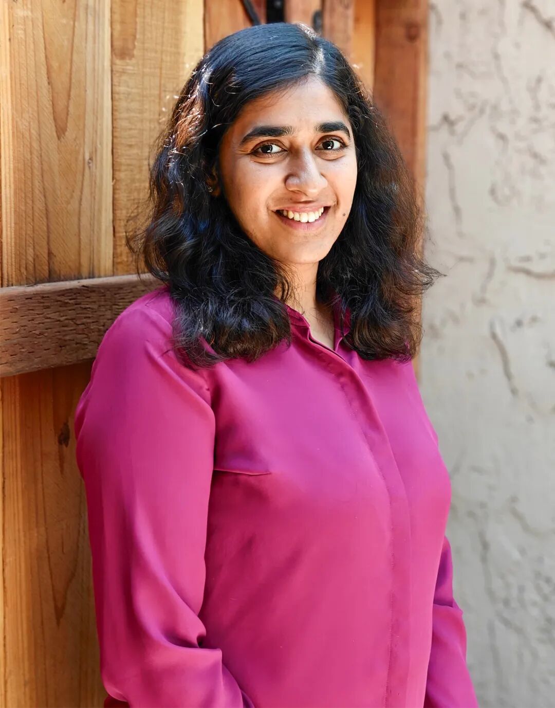 Dakshita Khurana standing outside in a pink shirt.